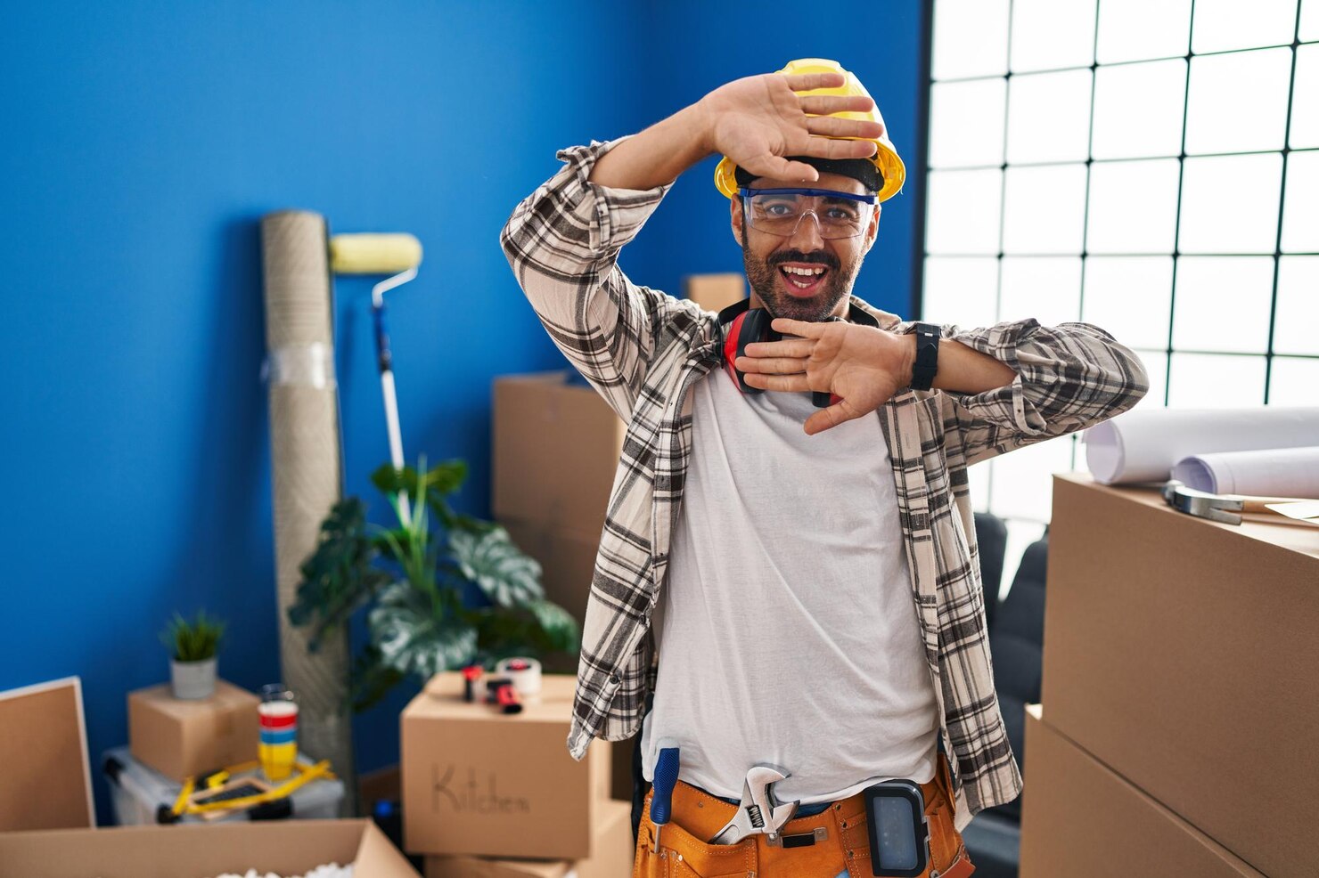 joven hispano barba trabajando renovacion hogar sonriendo alegre jugando peek boo manos mostrando cara sorprendida emocionada 839833 5465